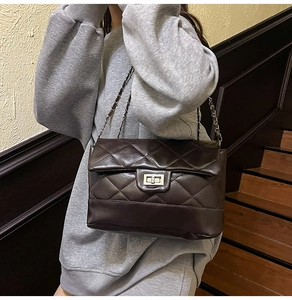 Detail of dark brown quilted crossbody bag with silver rotating clasp and chain strap