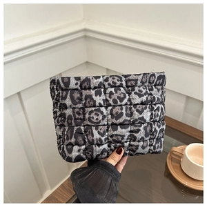 Detailed view of leopard print quilted clutch bag with zipper closure in a home setting