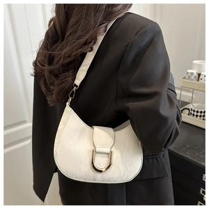 Detail of white hobo shoulder bag featuring a gold U-shaped buckle and textured leather finish