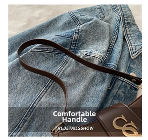 Detail view of dark brown leather handbag featuring a stylish gold metal logo buckle
