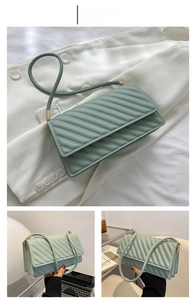 Détail du sac matelassé vert clair avec boucles dorées et coutures élégantes en gros plan