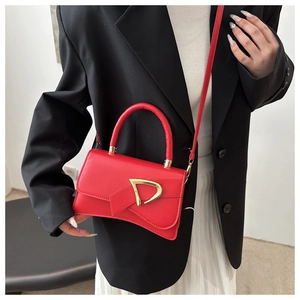 Dettaglio borsa quadrata in pelle rossa con fibbia dorata e tracolla elegante
