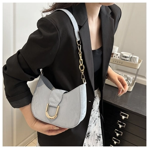 Close-up of light blue pleated croissant bag featuring a gold horseshoe metal buckle