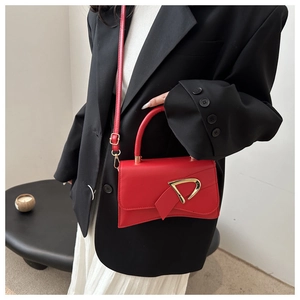 Dettaglio della borsa rossa a tracolla con fibbia dorata a D e nastro decorativo chic