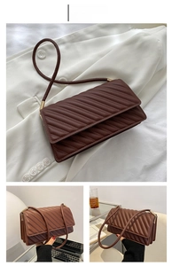 Détails d'un sac bandoulière marron foncé matelassé avec surpiqûres et métal doré