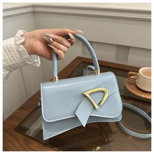 Dettaglio della borsa azzurra con fibbia a D dorata e patta asimmetrica dal design elegante