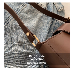 Detail of golden ring link connecting brown leather strap to minimalist square bag