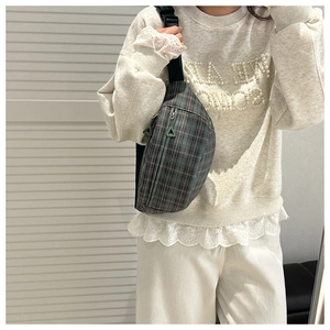 Detail view of a plaid crossbody bag with dual zipper pockets and adjustable black strap