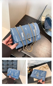 Detail of blue denim crossbody bag with frayed stripes and gold chain strap