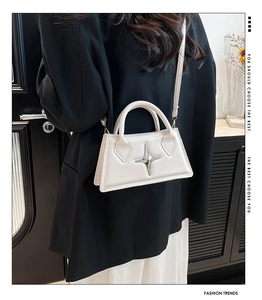 Détail d'un sac à main structuré blanc orné d'un accessoire métallique en forme d'étoile