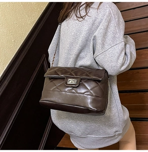 Detail of coffee brown quilted crossbody bag with metal chain strap and silver twist lock