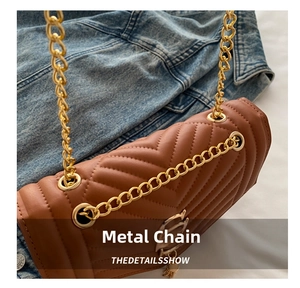 Detail of caramel quilted crossbody bag with chevron stitching and gold chain strap