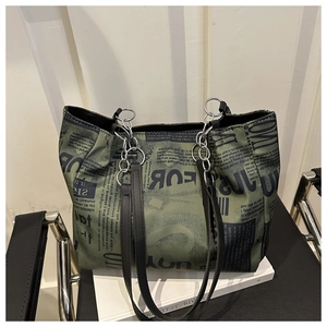 Dettaglio borsa tote verde militare con stampa di giornale e catena metallica