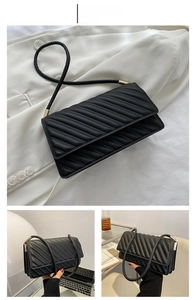 Détail du sac bandoulière en cuir noir avec texture plissée et attaches en métal doré
