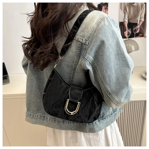 Detail of black wrinkled leather shoulder bag with silver U-shaped metal buckle on model