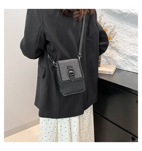 Détail du sac bandoulière noir élégant avec strass et rabat porté par le mannequin