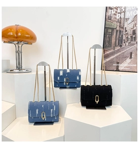 Detail of denim chain bags with frayed edges and gold clasps in blue and black