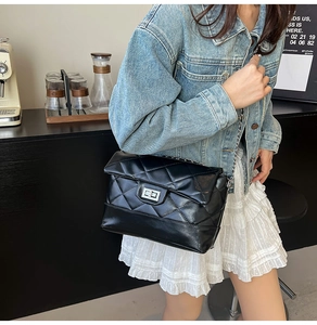 Detail of black quilted chain bag with silver twist lock and polished faux leather finish