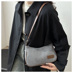 Detail of the gray woven fabric texture and brown leather strap on a shoulder bag