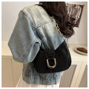 Detail of black half-moon shoulder bag with large gold buckle and metal chain strap
