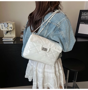 Detail of white quilted leather texture with silver metal chain strap and twist lock