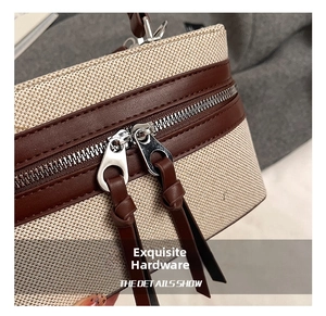 Detail of woven canvas and brown leather box bag with dual silver metal zippers
