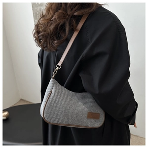 Detail of grey tweed shoulder bag with brown leather trim and golden metallic buckle