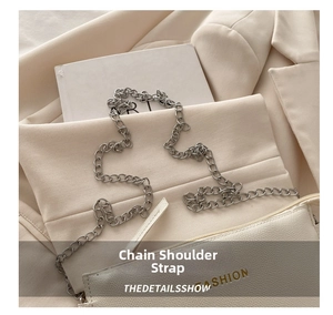 Detail of white litchi pattern crossbody bag with silver thick chain strap on blazer