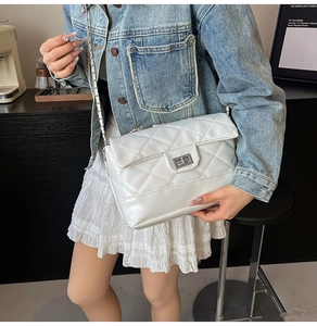 Close-up of white quilted crossbody bag with silver twist lock and chain strap on a model