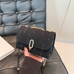 Black denim crossbody bag with distressed edge detailing and gold chain strap