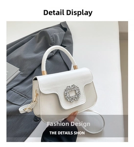 Detail of elegant white handbag featuring a sparkling rhinestone floral buckle on the front flap