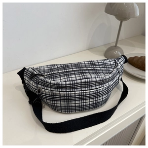 Detail of black and white plaid chest bag with adjustable strap on a minimal background