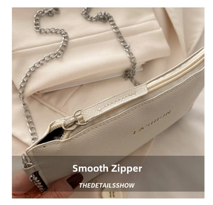 Detail of white litchi pattern leather bag with silver zipper and chain strap