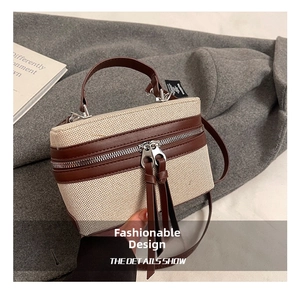 Detail of beige canvas box bag with brown leather trim and long zipper tassels