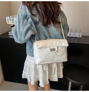 Modern white quilted crossbody bag with diamond stitching and metal chain strap on model