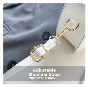 Detail of adjustable white leather strap with polished gold buckle and swivel snap hook