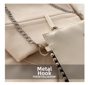 Detail of cream leather bag with silver metal lobster clasp and studded edge accents