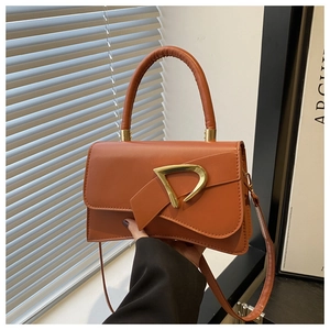 Dettaglio borsa in pelle arancione con fibbia a D dorata e patta curva dal design unico