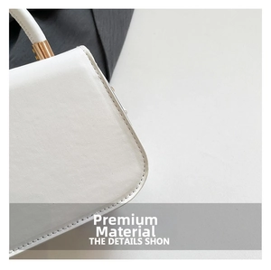 Close-up of white matte leather handbag featuring fine stitching and gold metal hardware