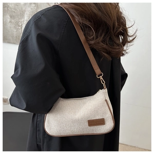 Detail of white tweed shoulder bag with brown leather trim shown on model's shoulder