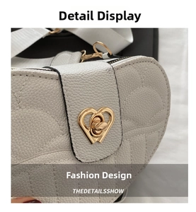 Detailed macro of a gold heart-shaped twist lock on a white lychee grain leather bag