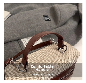 Detail of woven fabric handbag with brown leather handle and silver metal hardware