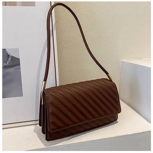 Gros plan du sac bandoulière marron foncé surpiqué avec des détails en métal doré