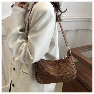Detail of dark brown corduroy shoulder bag showing vertical rib texture and leather patch