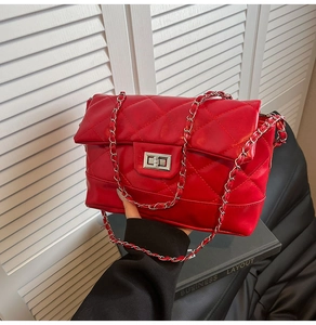 Macro shot of red quilted leather surface and silver metal chain strap on handbag