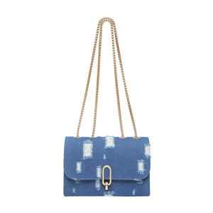 Blue denim crossbody bag with distressed patches and gold chain strap on white background