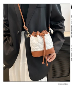 Quilted bucket bag with white lattice stitching and brown leather base shown on a model