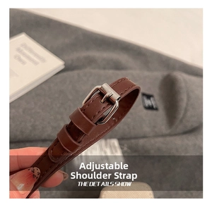 Detail of adjustable brown leather strap with silver buckle and fine stitching