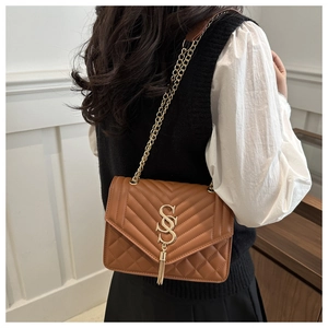 Close-up of brown quilted leather bag featuring gold V-stitch detail and chain strap