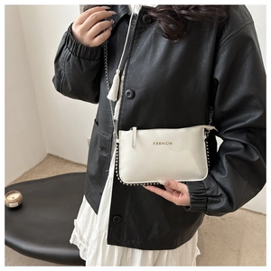 Detail of white PU leather crossbody bag with fringe, gold lettering and silver studs